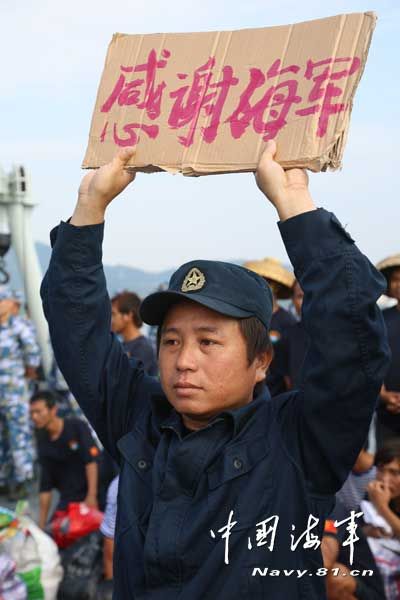 上圖為我官兵把作訓服贈送給獲救漁民穿